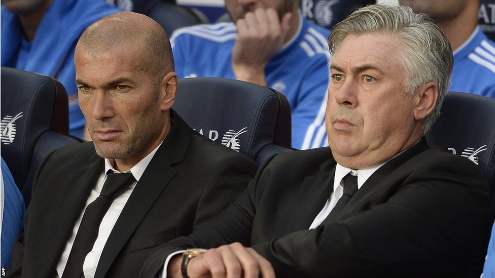 Zidane y Ancelotti sentados en un banquillo
