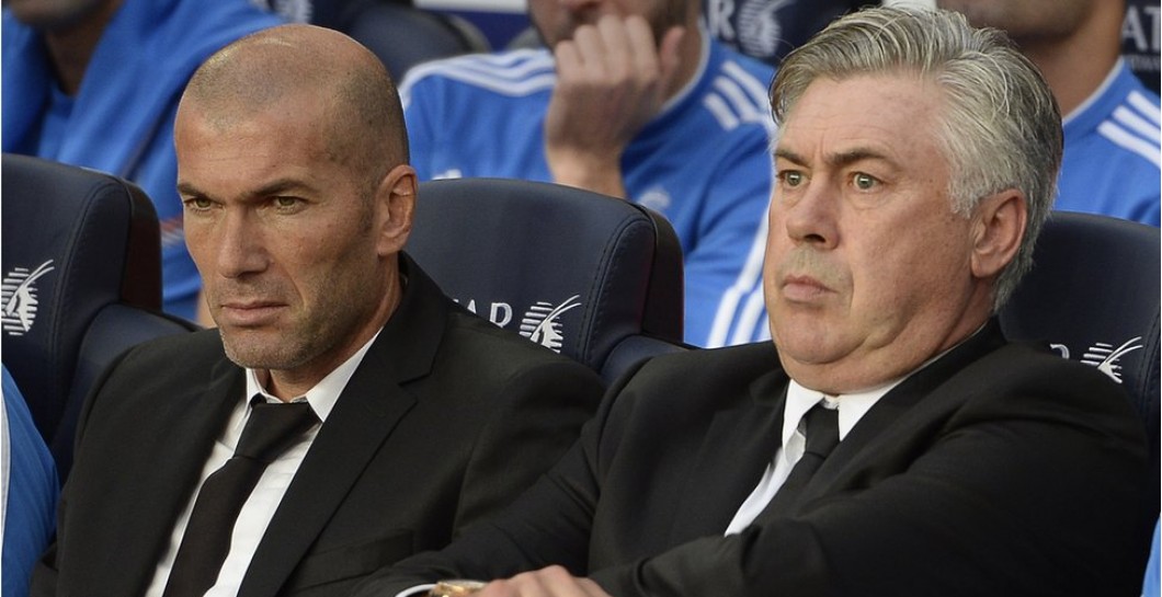 Zidane y Ancelotti sentados en un banquillo